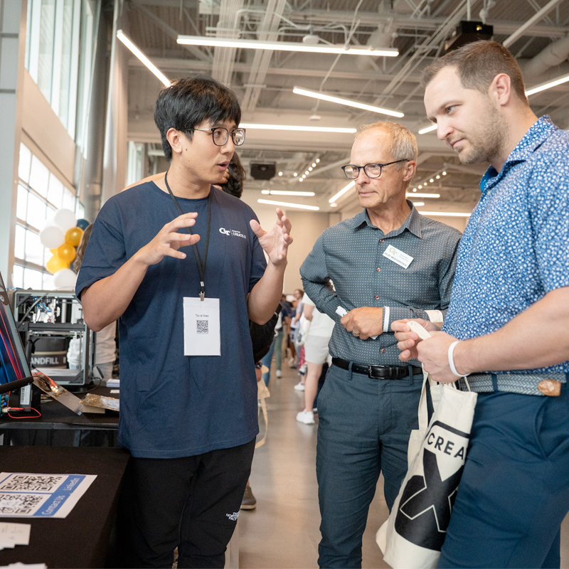 student describing his post to two researchers