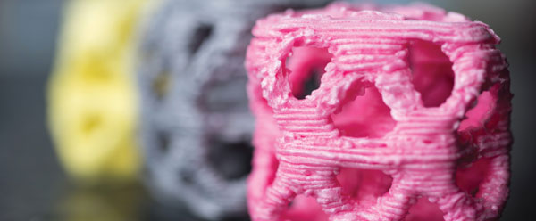 Close-up of 3D printed materials: pink, gray, and yellow