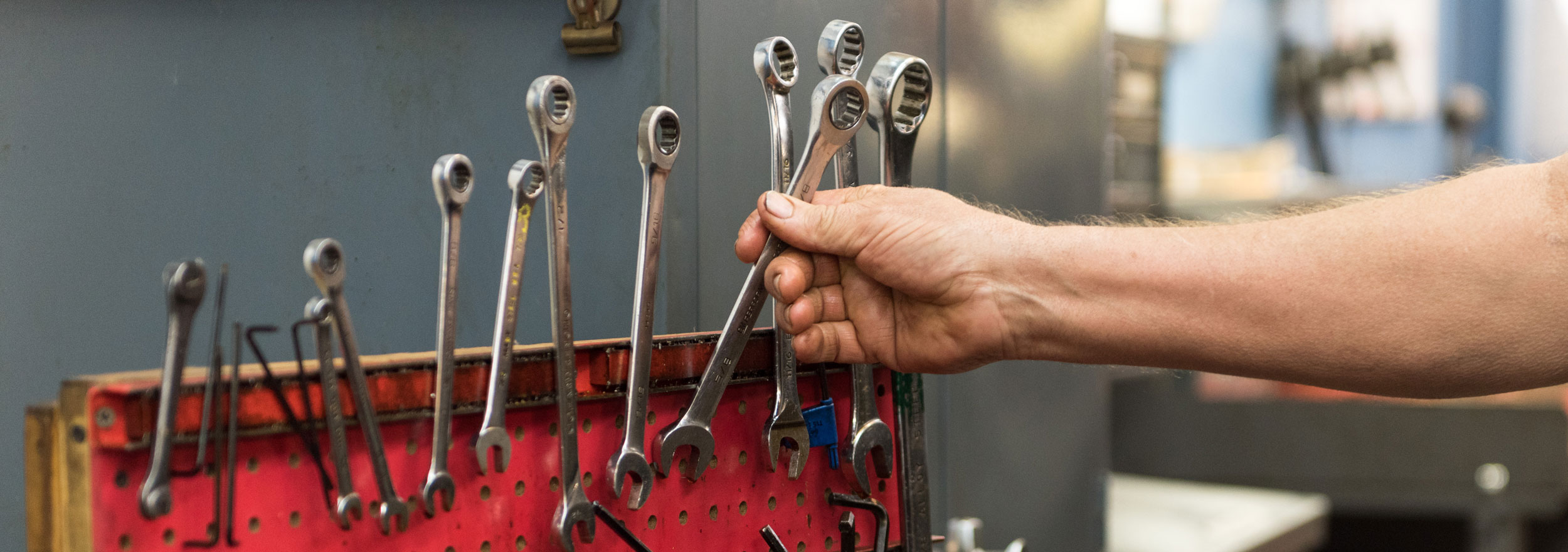 Hand reaching for wrench in red toolbox