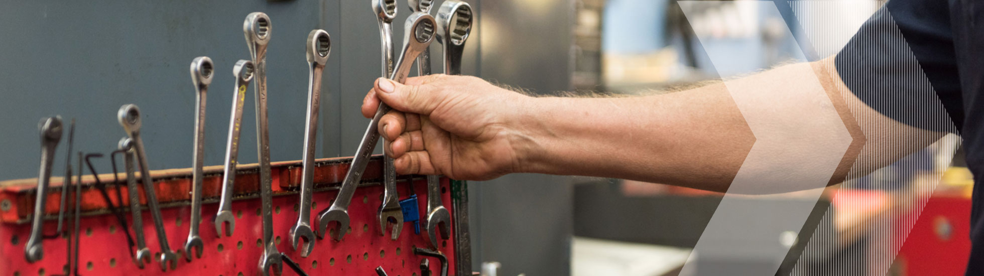 A hand reaching for a wrench in a red toolbox