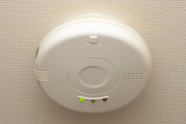 A round gas sensor is mounted to a white ceiling
