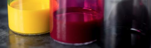 Three beakers of paint: red, yellow, and black